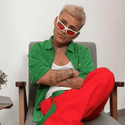 Man In Green Shirt And Red Pants Sitting With Arms Crossed GIF