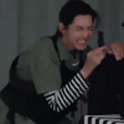 Man In Green Shirt And Striped Sleeves Sitting At Table GIF