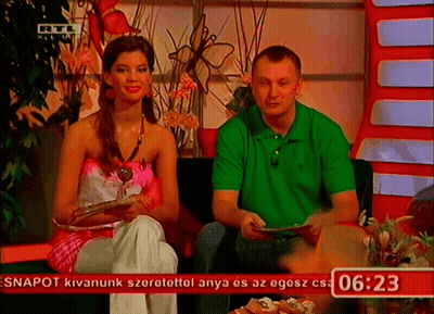 Man In Green Shirt And Woman In Pink Top In Front Of Screen Saying 06:23 GIF