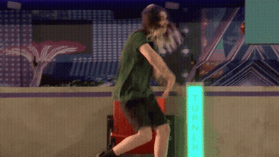 Man In Green Shirt Dancing In Front Of Turner Neon Sign GIF