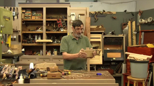 Man In Green Shirt Holding Piece Of Wood GIF