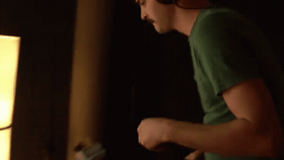 Man In Green Shirt Playing Guitar With Headphones GIF