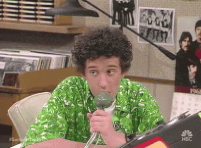 Man In Green Shirt Sitting At Table Holding Microphone GIF
