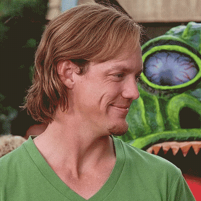 Man In Green Shirt Smiling In Front Of Monster GIF