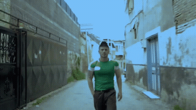 Man In Green Shirt Walking Alleyway GIF
