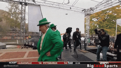 Man In Green Suit And Hat In Front Of NCAAF Sign GIF
