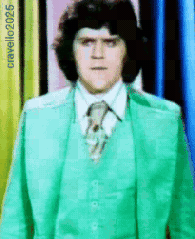 Man In Green Suit And Tie In Front Of Cravello2025 Sign GIF