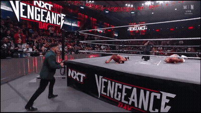 Man In Green Suit Standing Before Vengeance Sign GIF