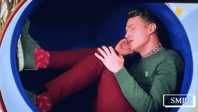Man In Green Sweater And Red Pants Lying In Blue Circle GIF