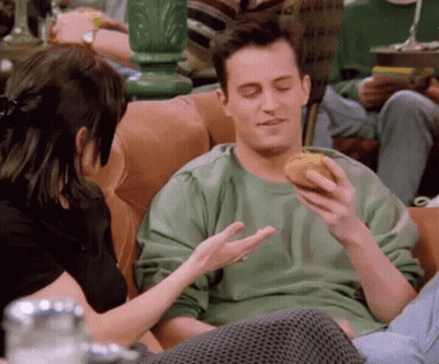 Man In Green Sweater Eating Donut On Couch GIF