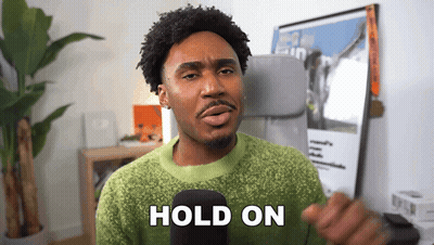 Man In Green Sweater Holding Microphone Saying Hold On GIF