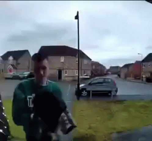 Man In Green Sweater On Sidewalk GIF