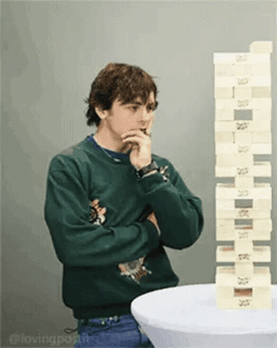 Man In Green Sweater Standing Next To Stack Of Blocks GIF