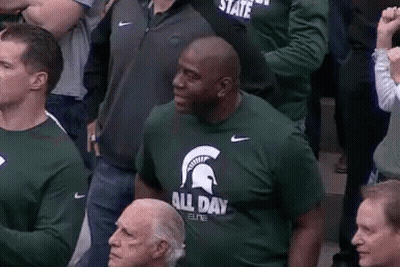 Man In Green T-Shirt With Spartan Helmet Sitting In Crowd GIF