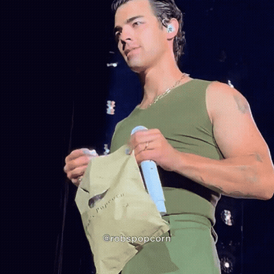 Man In Green Tank Top Holding Microphone And Popcorn GIF