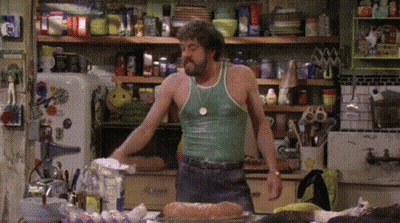 Man In Green Tank Top In Messy Kitchen GIF