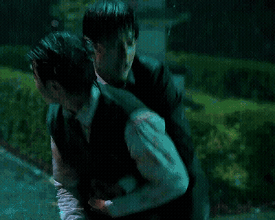 Man In Green Vest Carrying Another Man In Rain GIF