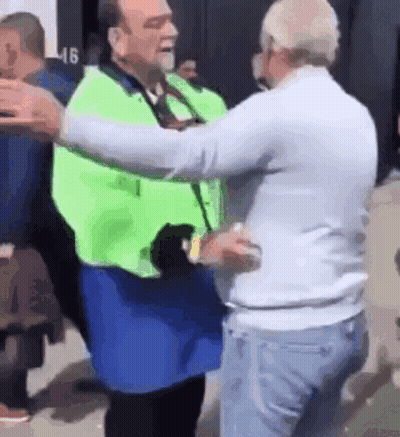 Man In Green Vest Hugging Man In White Shirt GIF