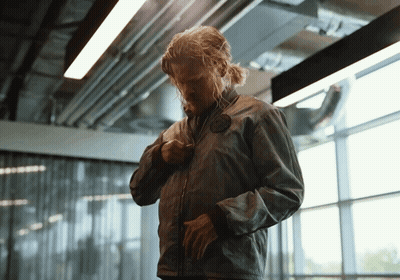 Man In Grey Jacket Standing In Front Of Glass Wall GIF