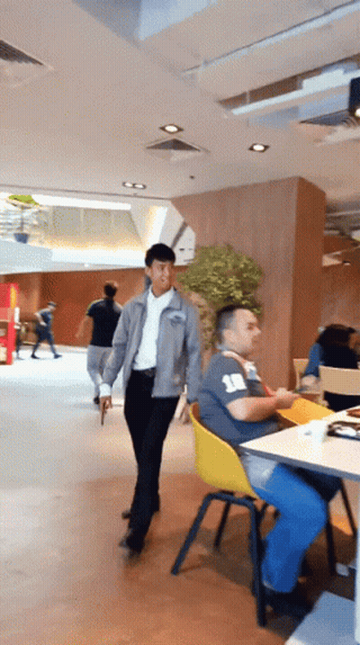 Man In Grey Jacket Walking Past Man With Number 18 Shirt GIF