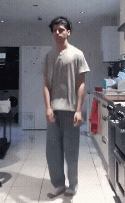 Man In Grey Shirt And Blue Pants Standing In Kitchen GIF