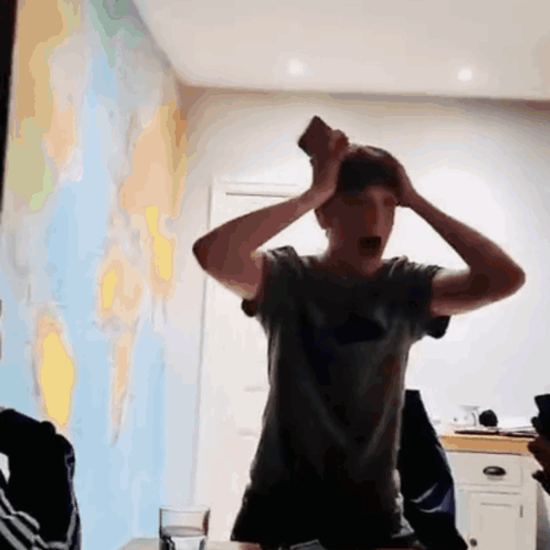 Man In Grey Shirt Holding Head In Front Of World Map GIF