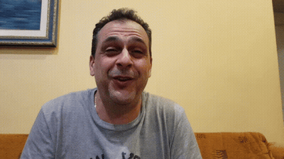 Man In Grey Shirt Saying A Sitting On Couch GIF