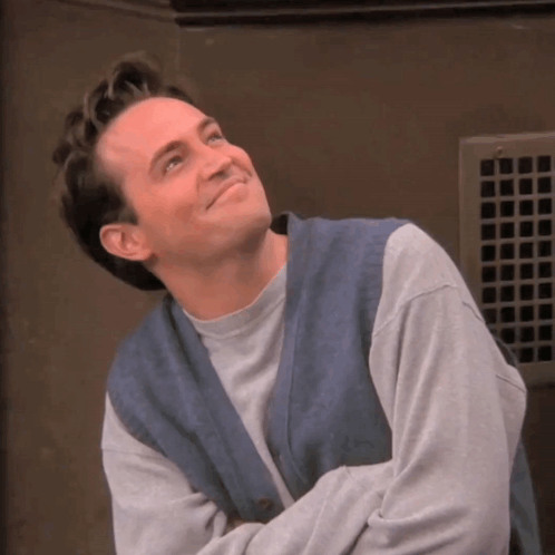 Man In Grey Sweater And Blue Vest Smiling GIF