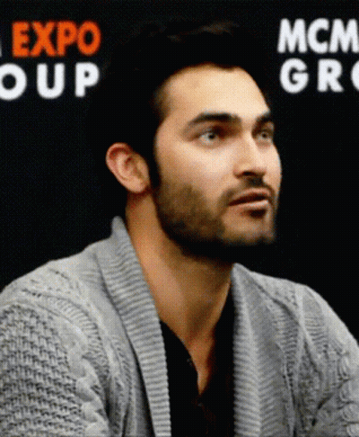 Man In Grey Sweater In Front Of Expo Group Sign GIF
