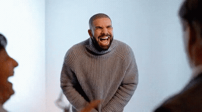 Man In Grey Sweater Laughing In Front Of Crowd GIF