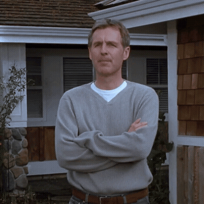 Man In Grey Sweater With Arms Crossed In Front Of House GIF