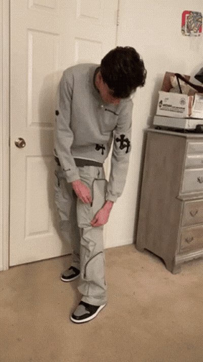 Man In Grey Sweatshirt And Cargo Pants Standing In Front Of Door GIF