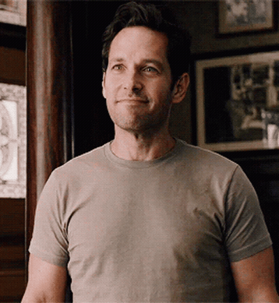 Man in Grey T-Shirt Smiling in Front of Picture Wall