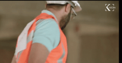 Man In Hard Hat And Safety Vest In Front Of K Media Screen GIF