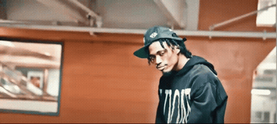 Man In Hat And Black Hoodie In Front Of Red Wall GIF