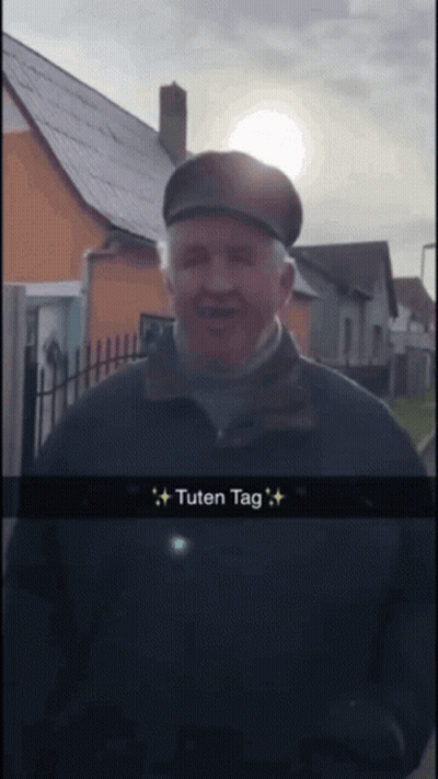 Man In Hat And Black Jacket In Front Of House Saying Tuten Tag GIF