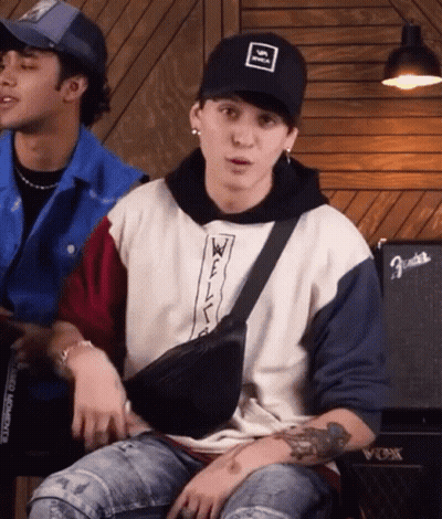 Man In Hat And Fanny Pack Sitting Next To Man In Hoodie GIF