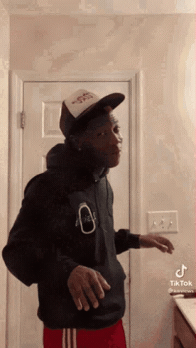 Man In Hat And Hoodie Standing In Bathroom GIF