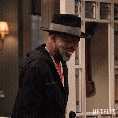 Man In Hat And Jacket Standing Before Netflix Door GIF