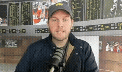 Man In Hat And Jacket Talking Into Microphone GIF