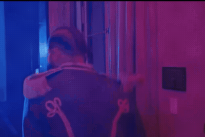 Man In Hat And Jacket With S On Back In Purple Room GIF