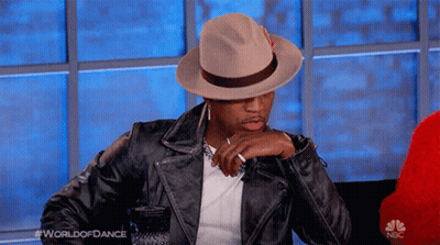 Man In Hat And Leather Jacket Sitting In Front Of NBC Logo GIF