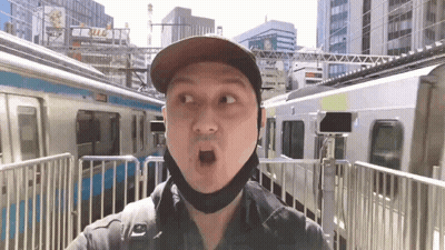 Man In Hat And Mask By Fence And Train GIF