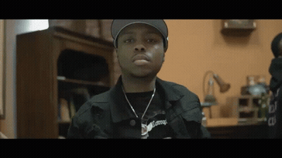 Man In Hat And Necklace Looking At Camera GIF