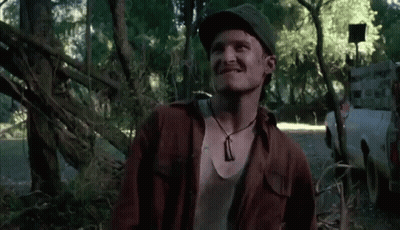 Man In Hat And Necklace Smiling In Woods GIF