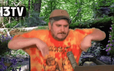 Man In Hat And Orange Shirt Talking Into Microphone In Front Of 13 TV Sign GIF