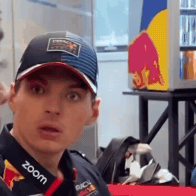 Man In Hat And Red Bull Shirt Looking At Camera GIF