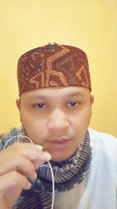 Man In Hat And Scarf Holding Earbuds GIF