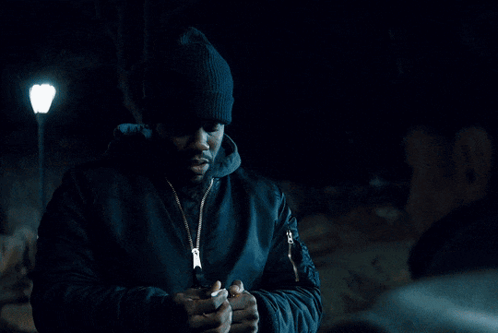 Man In Hat And Scarf Looking At Camera GIF