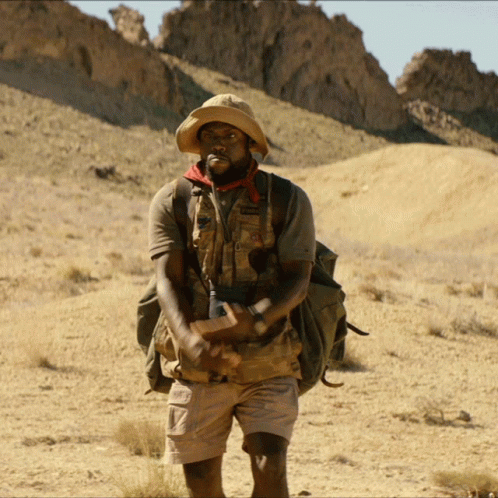Man In Hat And Shorts With Backpack In Desert GIF